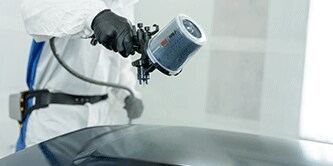 Técnico de pintura pulverizando piezas soltas.
