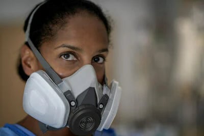 Imagen de la cara de una mujer usando un respirador reutilizable 3M.
