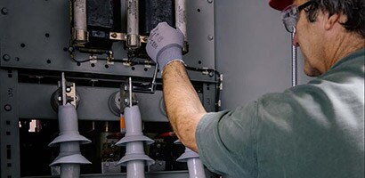 Un hombre controla componentes eléctricos para que la red siga funcionando de manera confiable y eficiente.
