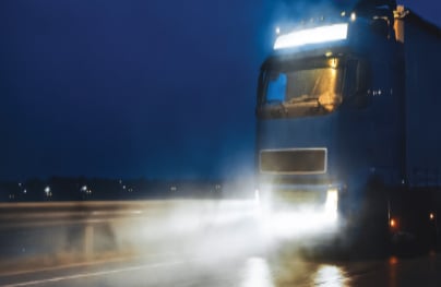Camión de hidrógeno conduciendo en la noche por una carretera mojada.