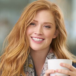 A smiling woman, holding a mug.