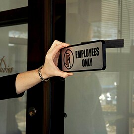 Image of a hand attaching Employees Only sign to glass using 3M™ Hook and Loop
