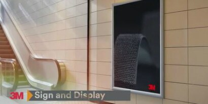 Video still of a display sign near an escalator with the text “Sign and Display”
