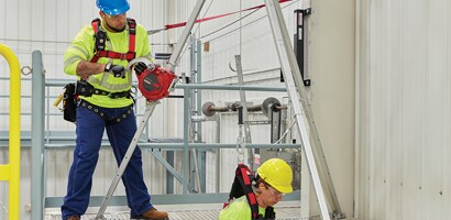 Workers demonstrating portable confined space retrieval tripod 
