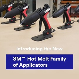 Five hot melt applicators on a table with a workshop in the background