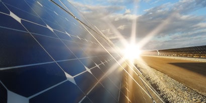 Solar panels producing solar energy with a sun in the background
