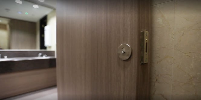 Miniatura de video de una puerta del área de un baño renovada y cubierta con acabados arquitectónicos 3M DI-NOC en tonos de madera oscura.
