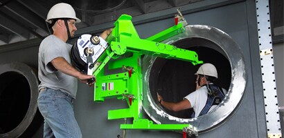 Worker operating horizontal confined space entry device at opening in side of large tank
