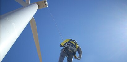 Worker suspended at end of long cable from wind turbine
