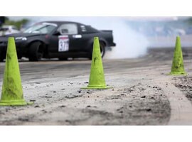 Imagen fija de video de un automóvil pasando por los conos de los límites en una pista de carreras