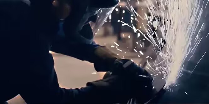 Trabajador metalúrgico usando un producto abrasivo para soldadura y fabricación de metal.
