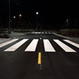 Low-angle shot of white painted crosswalk across road.