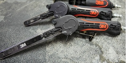 Persona colocando una cubierta plástica transparente sobre un automóvil negro en un espacio de trabajo.
