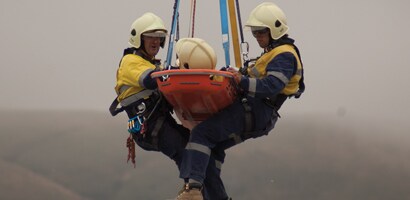 Two rescue workers and injured worker in a litter suspended from rescue device
