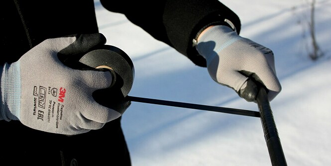 Un trabajador envolviendo un cable eléctrico con la cinta aislante 3M Super 33+®.
