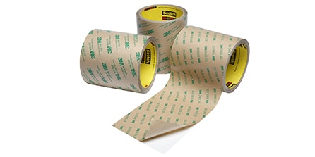 Image of three different rolls of double sided tapes, one with the liner partially peeled back
